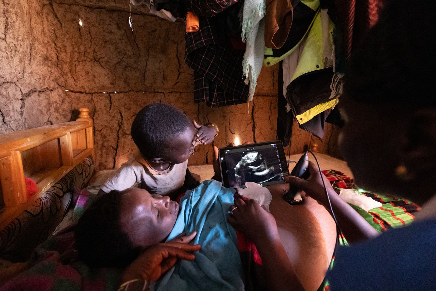 Pendi Lodonfokiuk, pregnant with her sixth child, and her young son look together at a phone-based ultrasound screen as nurse Lucy Makena scans her in a mud hut during a mobile outreach, Samburu County, Kenya.